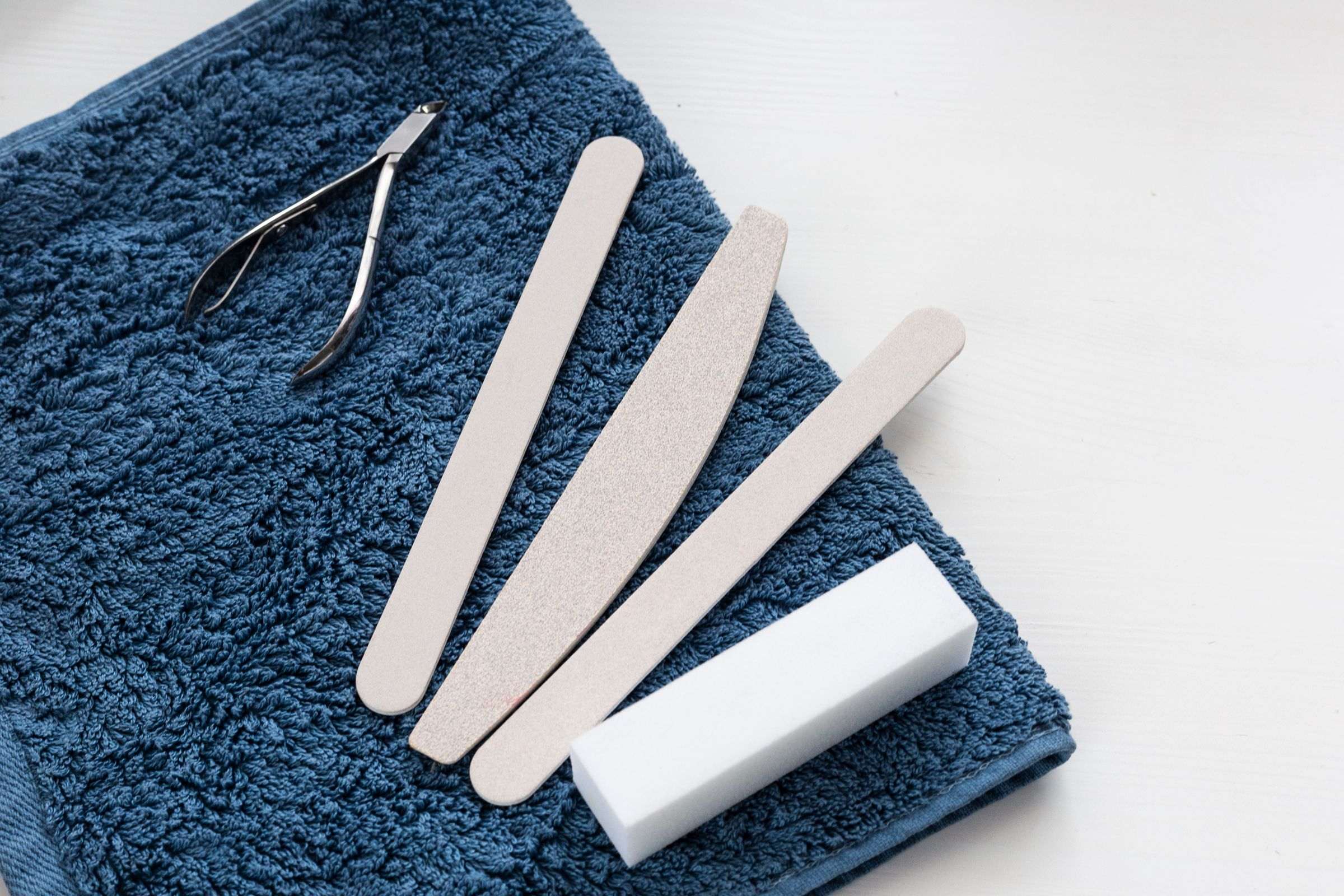 Limes à ongles, bloc polissoir et pince à cuticules sur une serviette